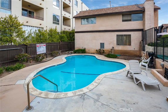 Outdoor swimming pool next to a two-story building.