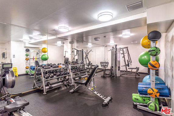 Indoor gym area with exercise equipment and weights.
