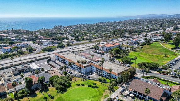 Aerial view of a coastal town with residential buildings and a highway, overlooking the ocean.