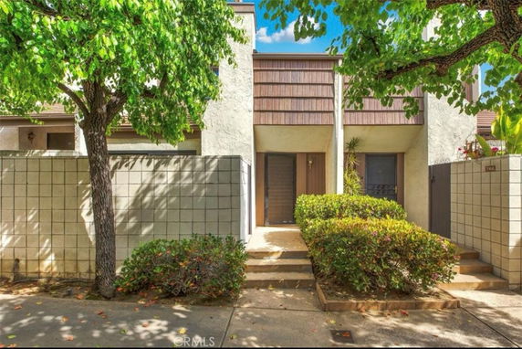 Front view of a two-story townhouse with a block wall and landscaped entry.