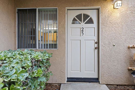 Front view of an entryway with a white door labeled 25, and a window with vertical blinds beside it.
