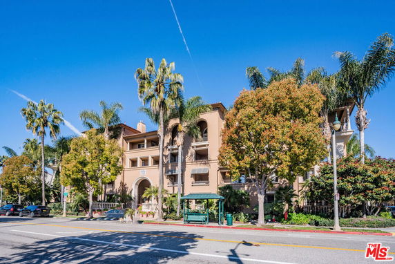 Front view of a multi-story residential building with balconies and arched entrance.