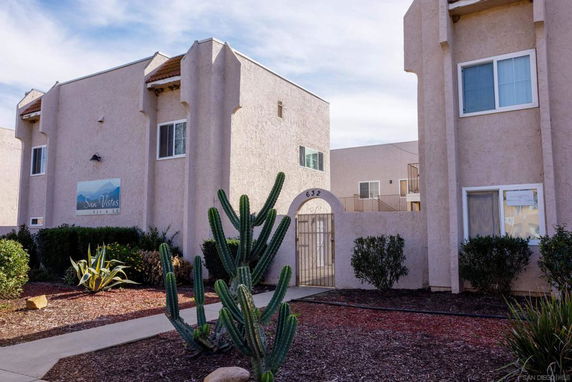Front view of a multi-story apartment building with a gated entrance.