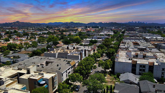 Panoramic view of a cityscape with residential and commercial buildings under a colorful sky.