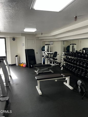 Indoor gym area with workout equipment, benches, and weights.