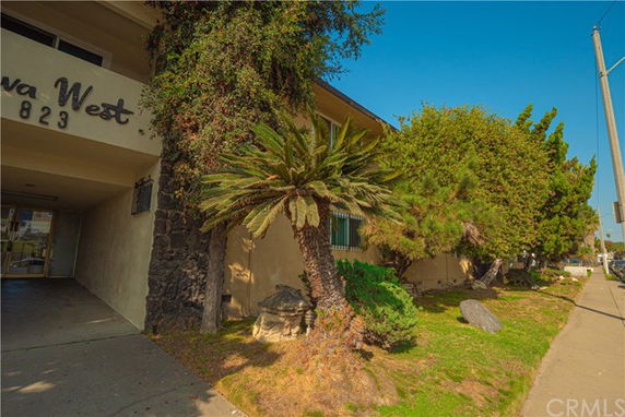 Front view of a building with trees and shrubs nearby.