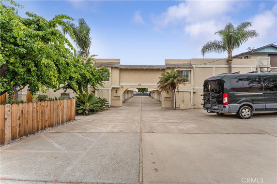 Outdoor parking area in front of a building with driveway under an arch.