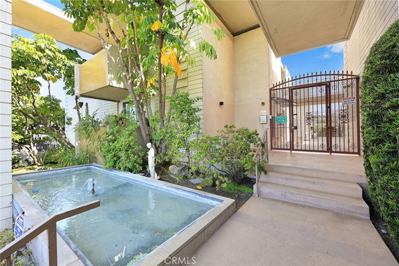 Front view of a building entrance with a small fountain and gated entry.