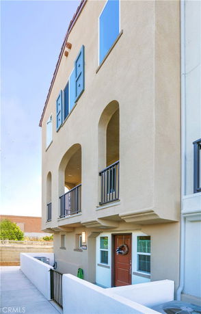 Front view of a multi-story house with balconies and arched windows.