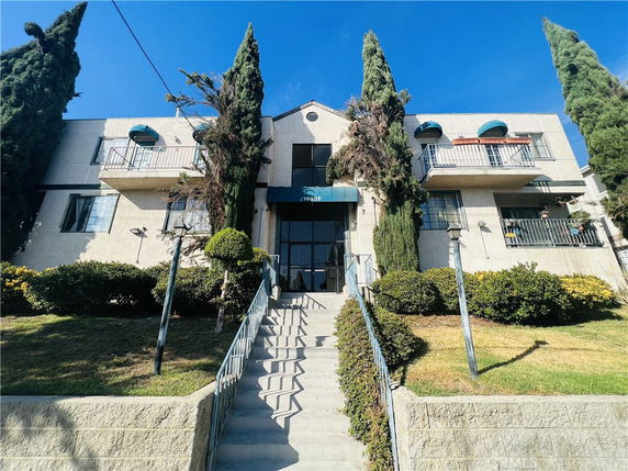 Front view of a multi-story residential building with a central staircase and balconies.