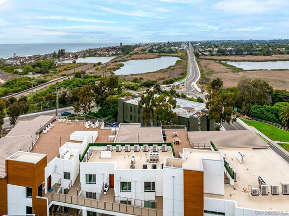 Aerial view of a building rooftop with surrounding landscape and water bodies.