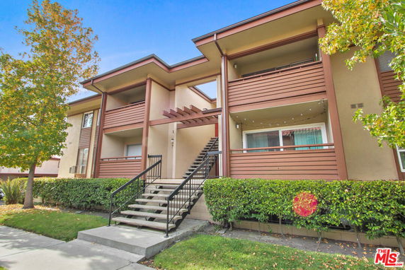 Front view of a two-story apartment building with stairs leading to the entrance.