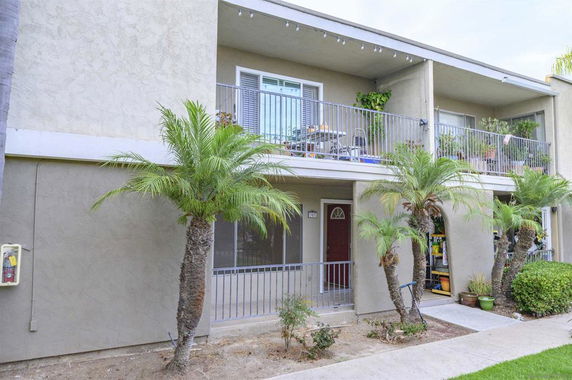 Front elevation of a two-story apartment building with balconies and palm trees.