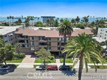 Front view of a multi-story apartment building with balconies and palm trees.