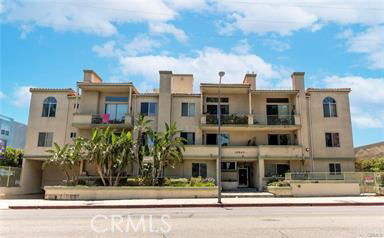 Front view of a multi-story building with balconies and arched windows.