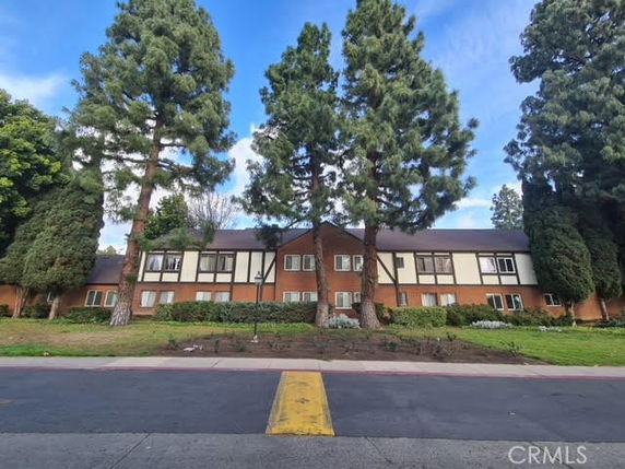 Front view of a two-story brick building with large trees in front.
