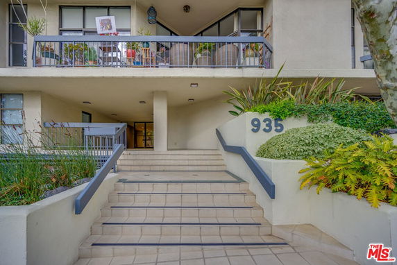 Front view of a multi-story building with a staircase entry and visible balconies.