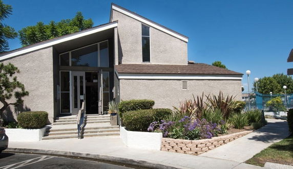 Front view of a modern building with a sloped roof and large windows.