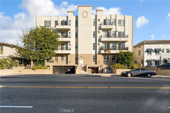 Front view of a multi-story residential building with balconies and a central entrance.