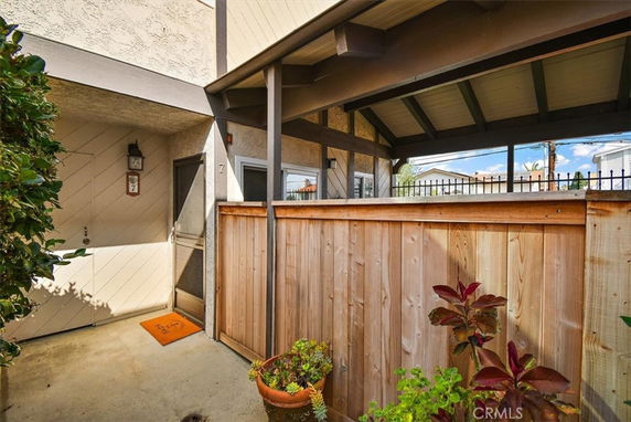Partial front view of a house with a wood fence and patio area.