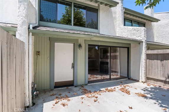 Front view of a two-story house with sliding glass doors and a wooden fence.