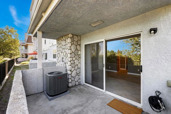 Patio view with a sliding glass door and outdoor air conditioning unit.
