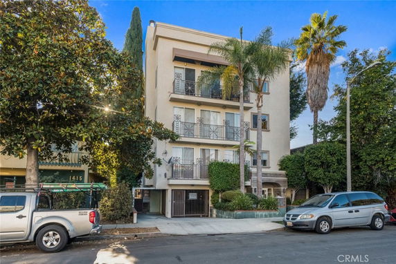 Front view of a multi-story apartment building with balconies and gated entrance.