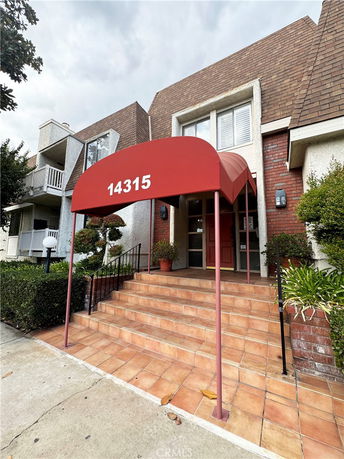 Front view of a building with tiled steps and a red awning above the entrance.