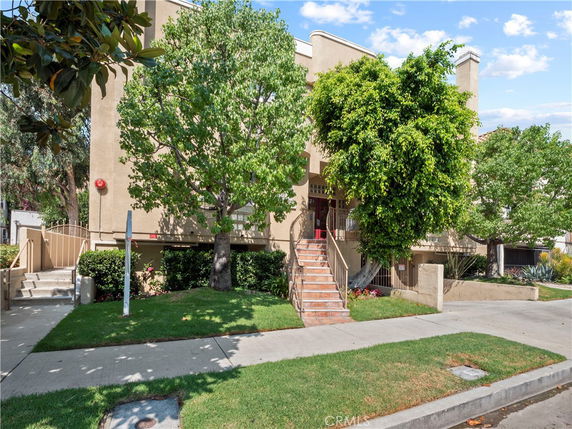 Front view of a multi-story residential building with stairs leading to the entrance.