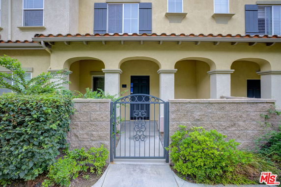 Front view of a house with an arched porch and gated entrance.