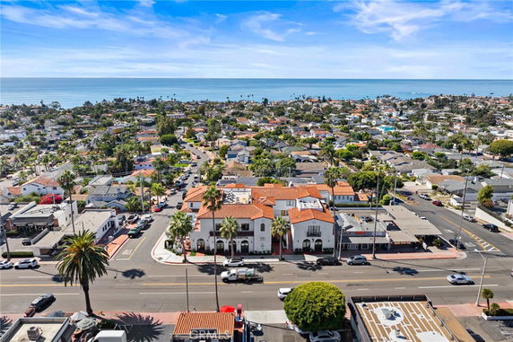 Aerial view of a coastal residential area with houses and buildings, overlooking the ocean in the background.
