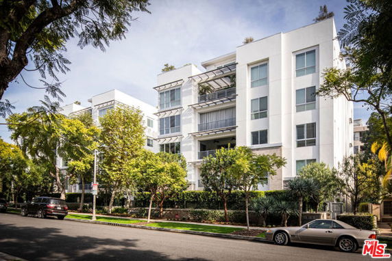 Front view of a modern multi-story apartment building with large windows.