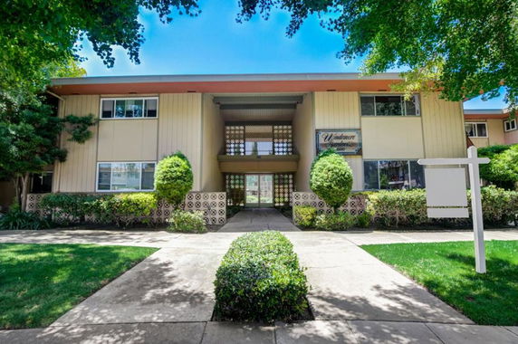 Front view of a two-story apartment building with beige exterior and large windows.