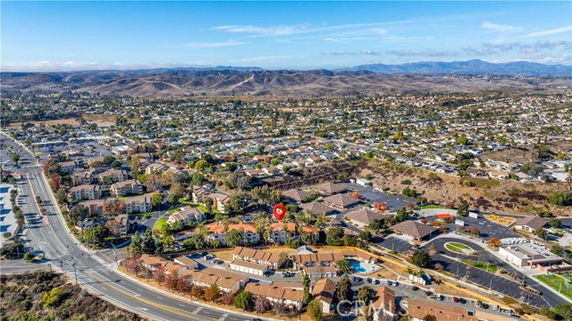Wide aerial view of a suburban area with residential and commercial buildings surrounded by hills.