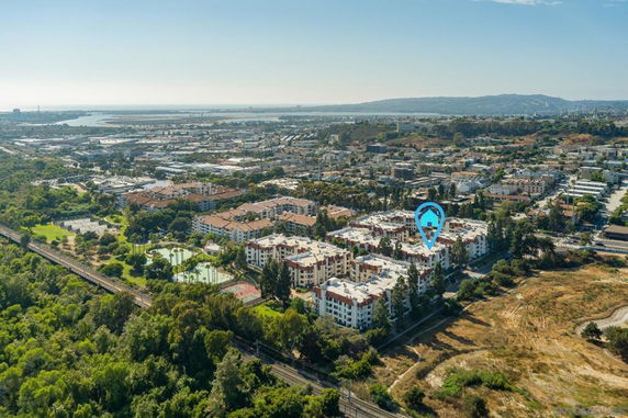Aerial view of a residential complex surrounded by greenery and urban landscape.
