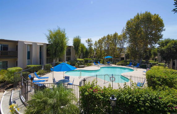 Outdoor swimming pool area surrounded by apartment buildings and trees.