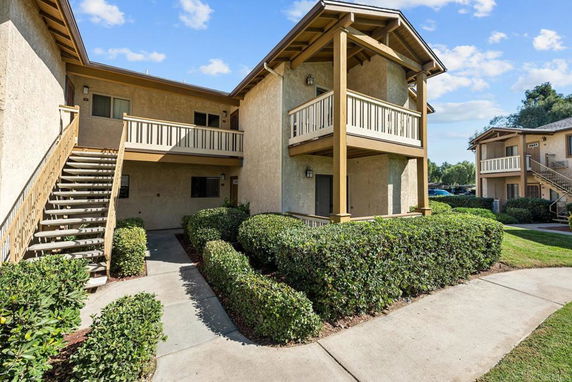 Front view of a two-story apartment building with a staircase and balcony.