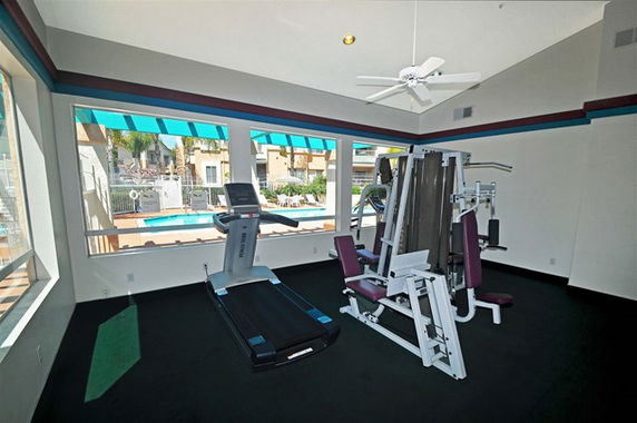 Indoor gym area with exercise equipment and large windows.