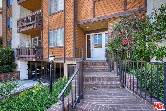 Front view of a multi-story building with brick steps and wooden balconies.