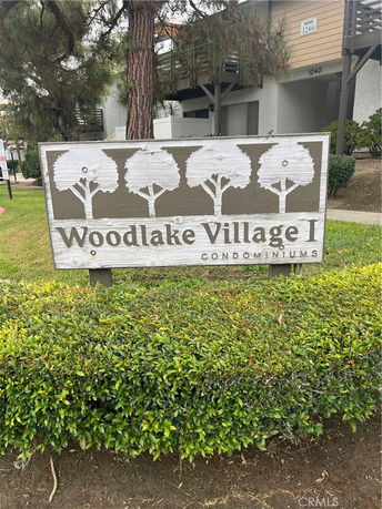 Front view of a condominium building with a sign reading 'Woodlake Village I Condominiums'.