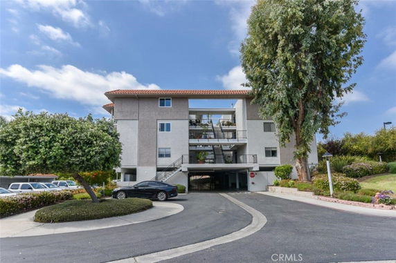 Front view of a multi-story residential building with a parking area below.