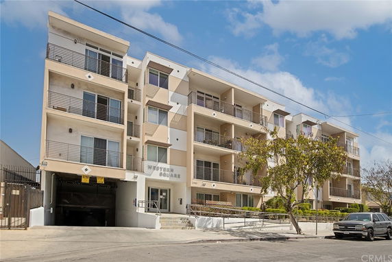 Front view of a multi-story residential building with balconies and garage entrance.