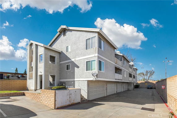 Front and side view of a multi-story residential building with multiple garages.