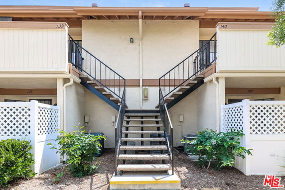 Front view of a two-story building with central staircase and upper balconies.