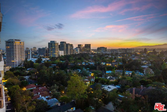 Panoramic view of a cityscape at sunset, high-rise buildings, and residential areas visible.