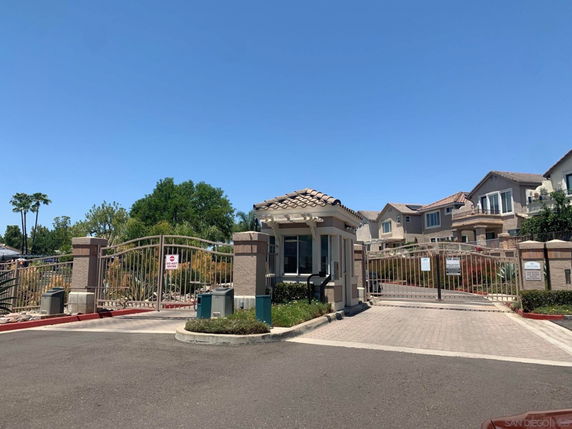 Gated entrance with a small security booth in front of residential buildings.