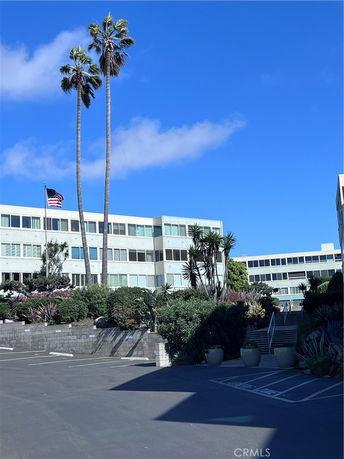 Front view of a multi-story building with large windows and surrounding palm trees.