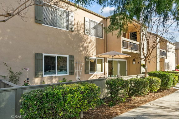 Front view of a two-story building with balconies and a fenced patio area.