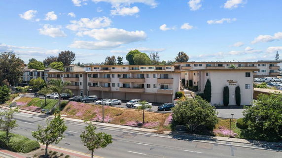 Front view of a multi-story apartment building with a parking area in front.