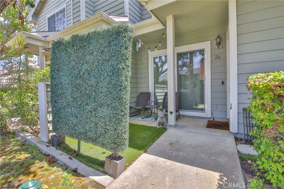 Front view of a house with a porch and artificial hedge screen.